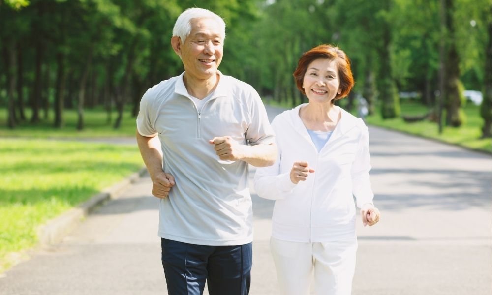 Người lớn tuổi vận động nhẹ nhàng đi bộ ngoài trời để duy trì sức khỏe xương khớp dẻo dai