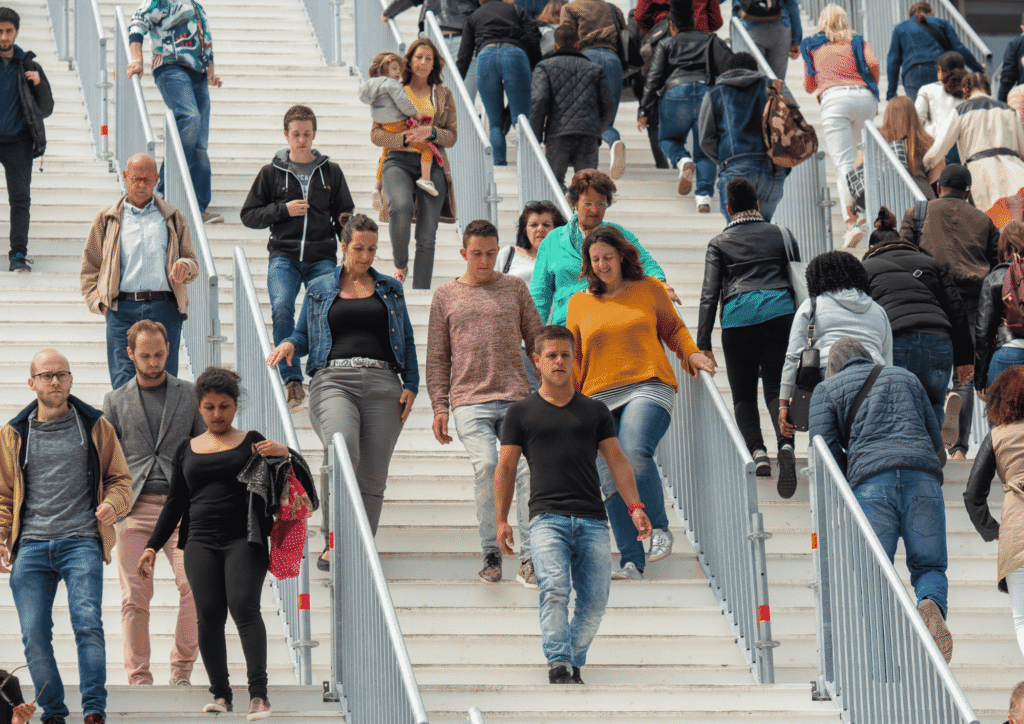 A crowd of people walking on outdoor stairs feeling calf fatigue