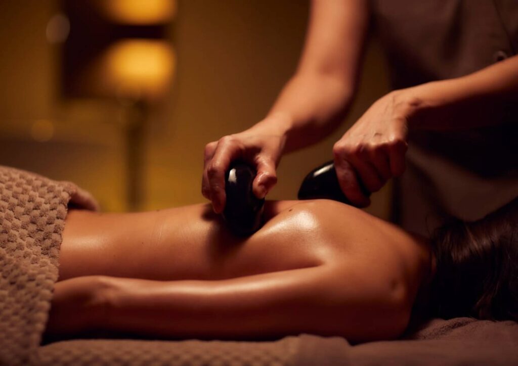 Therapist applying heated stones during a deep tissue hot stone massage therapy session